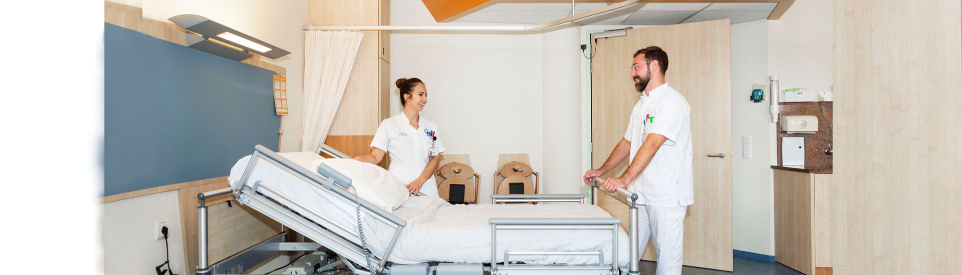 Twee verpleegkundigen in een verpleegkamer bij een bed Twee verpleegkundigen in een verpleegkamer bij een bed