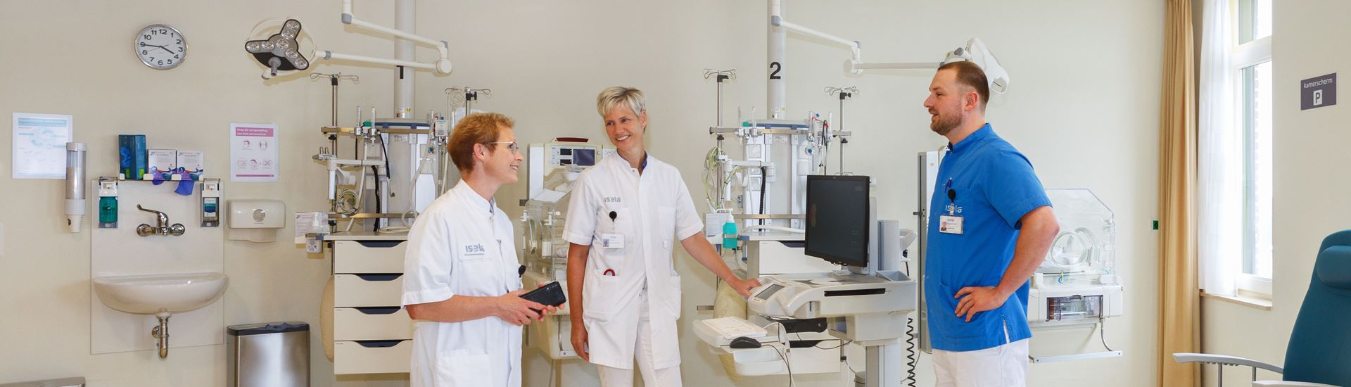 Drie verpleegkundigen in gesprek op een verpleegafdeling Drie verpleegkundigen in gesprek op een verpleegafdeling